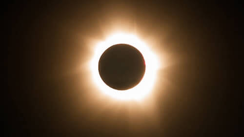 Fotografía de un eclipse solar durante la fase de totalidad. Se aprecia un circulo negro, rodeado de un halo de luz: La corona o atmósfera solar