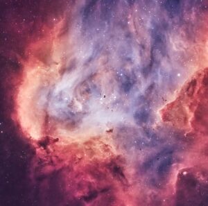 Descripción de imagen: Acercamiento al centro de la nebulosa, que se aprecia como una nube de gas y polvo, de color rojo en los bordes y azul y celeste en el centro. En la parte central se distinguen unos pequeños bultos oscuros, los llamados Glóbulos de Bok, junto a estrellas brillantes. 